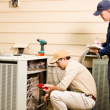 A technician seeing if an AC unit is working properly during AC inspection and maintenance in Bloomington IL