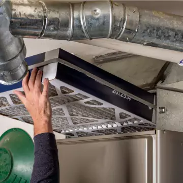 A person replacing a furnace filter